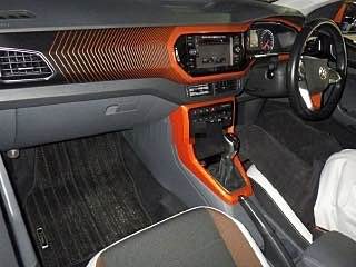 Салон Volkswagen T‑Cross 2021 с яркой оранжевой декоративной отделкой на торпедо, центральной консоли и руле; видны приборная панель и передние сиденья.
