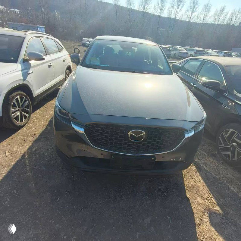 Mazda CX-5 на открытой стоянке: ровный фронтальный вид автомобиля среди других машин в порту или складе ожидания отправки.