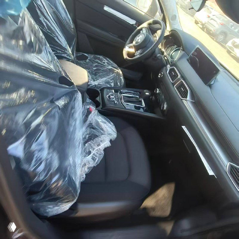 Салон Mazda CX-5: передние сиденья в защитной плёнке, панель приборов и рулевое колесо, интерьер нового автомобиля.