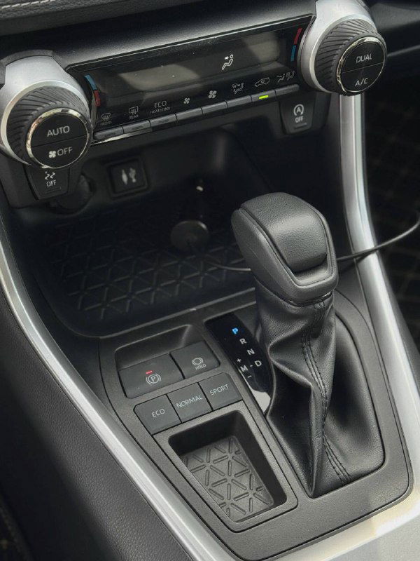 Селектор вариатора и панель в центральной части салона Toyota RAV4, клавиши управления и подстаканники видны в рабочем состоянии.