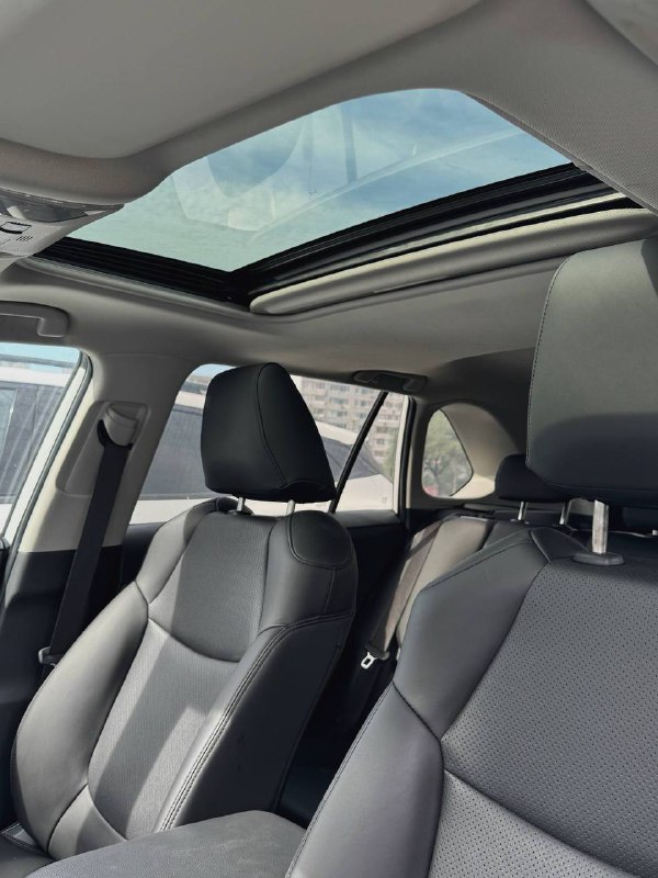 Крыша и панорамный люк салона Toyota RAV4, вид на верхнюю часть передних сидений и стеклянный люк в раскрытом состоянии обеспечивает естественное освещение.