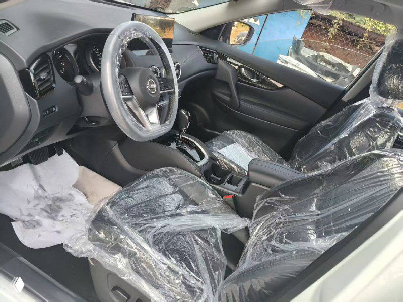 Салон Nissan X‑Trail с защитной плёнкой на креслах, вид на руль и переднюю панель — фото новых авто перед отправкой из Китая.