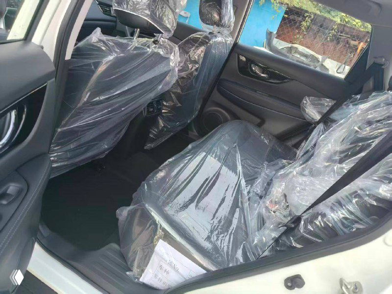 Задние сиденья Nissan X‑Trail с полиэтиленовой защитой, интерьер чёрного цвета — демонстрация состояния нового автомобиля перед экспортом.