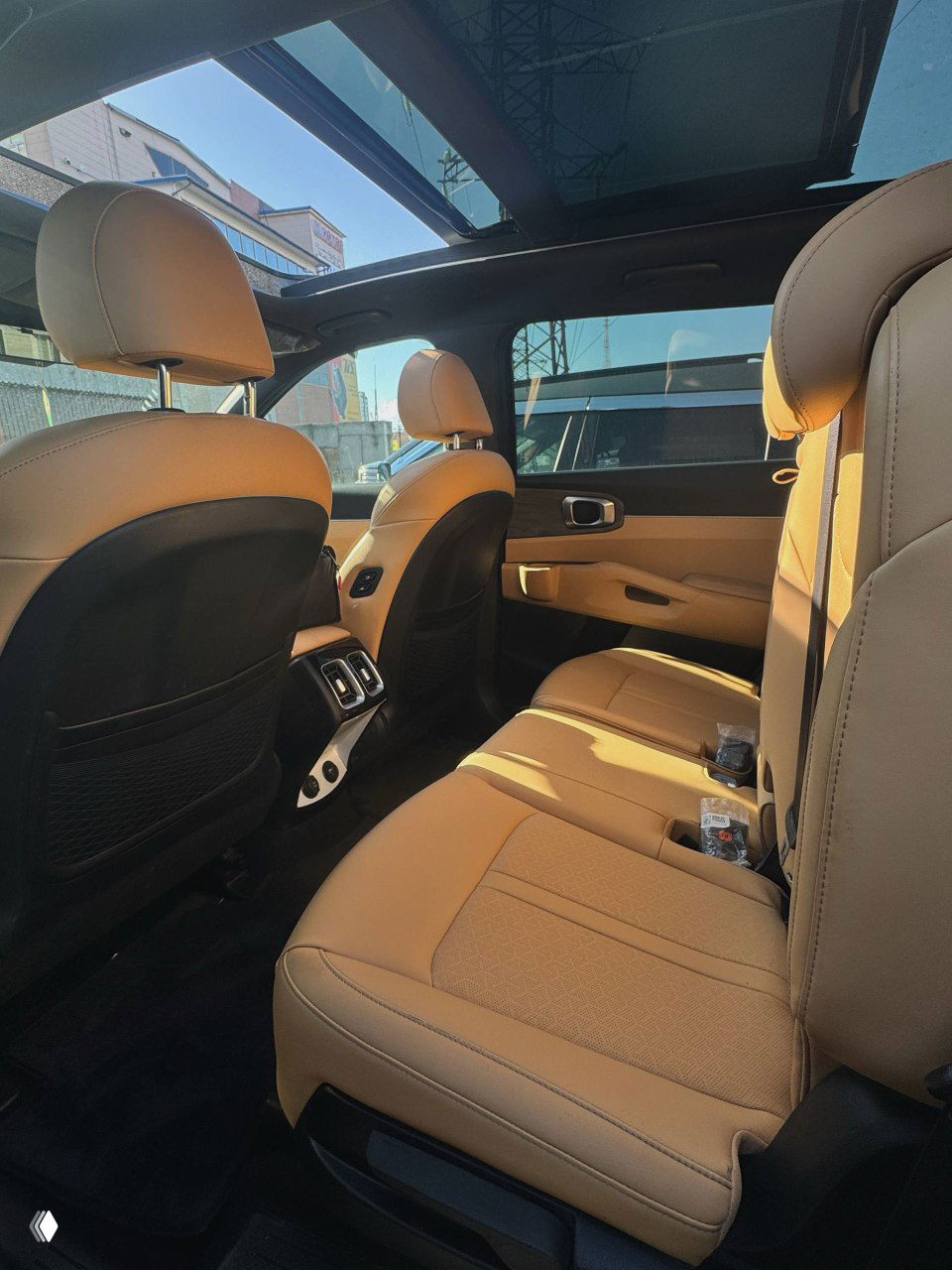 Задний ряд сидений KIA Sorento: трёхместный диван в бежевой обивке, видна ножная зона и воздуховоды заднего климата, общая аккуратность салона.