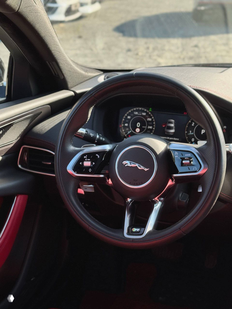 Руль и приборная панель Jaguar XE L: многофункциональный руль с логотипом Jaguar и цифровая панель приборов на фоне салона.