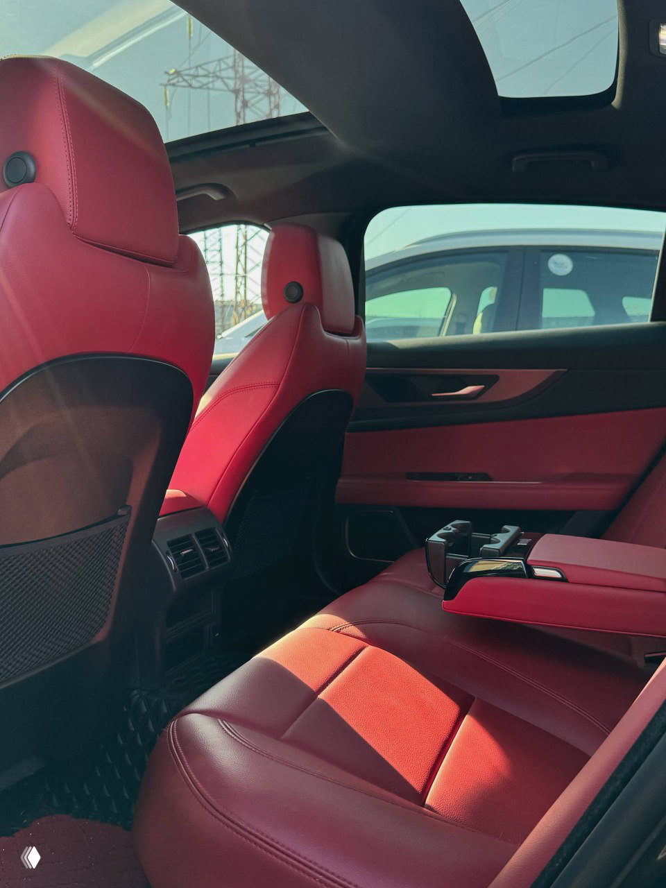 Задний ряд сидений Jaguar XE L с красной кожаной обивкой; видна центральная консоль для задних пассажиров и пространство для ног.