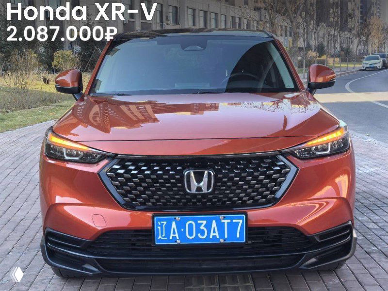 Honda XR-V оранжево-красного оттенка, вид спереди на уличной парковке; на фото указана цена 2.087.000₽ и номерной знак Китая, подчёркнуты фары и решётка радиатора.