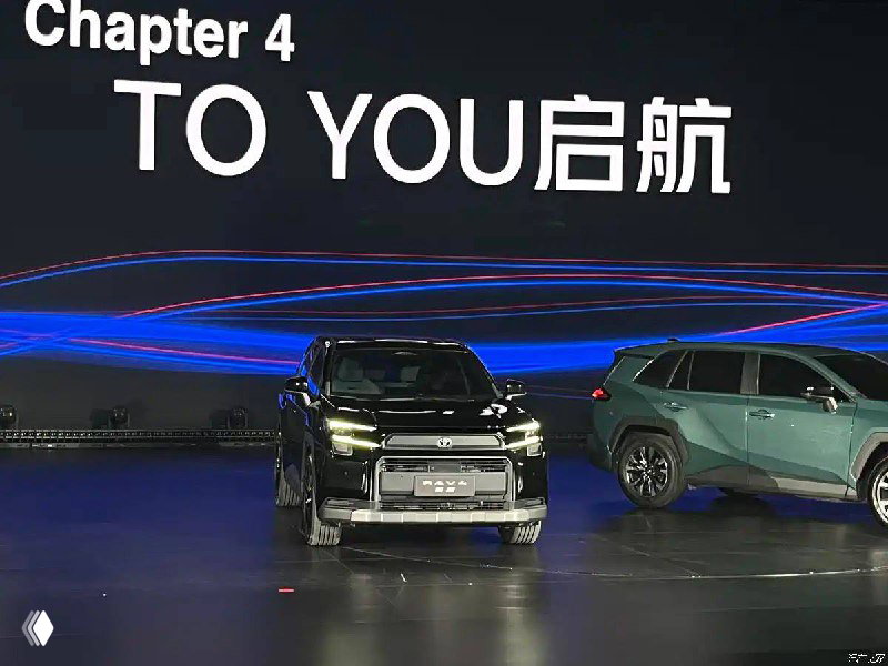 Несколько версий RAV4 на сцене презентации в Гуанчжоу на фоне большого экрана с надписью, видны разные цветовые исполнения кузова.