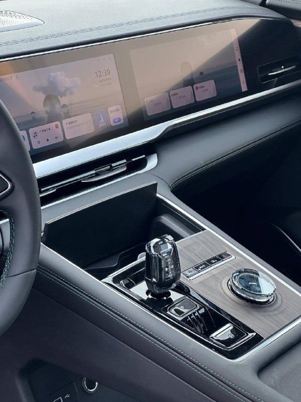 Крупный план центральной консоли Geely Monjaro 2025: селектор передач, шайба управления и отделка вокруг панели управления мультимедиа и климата.