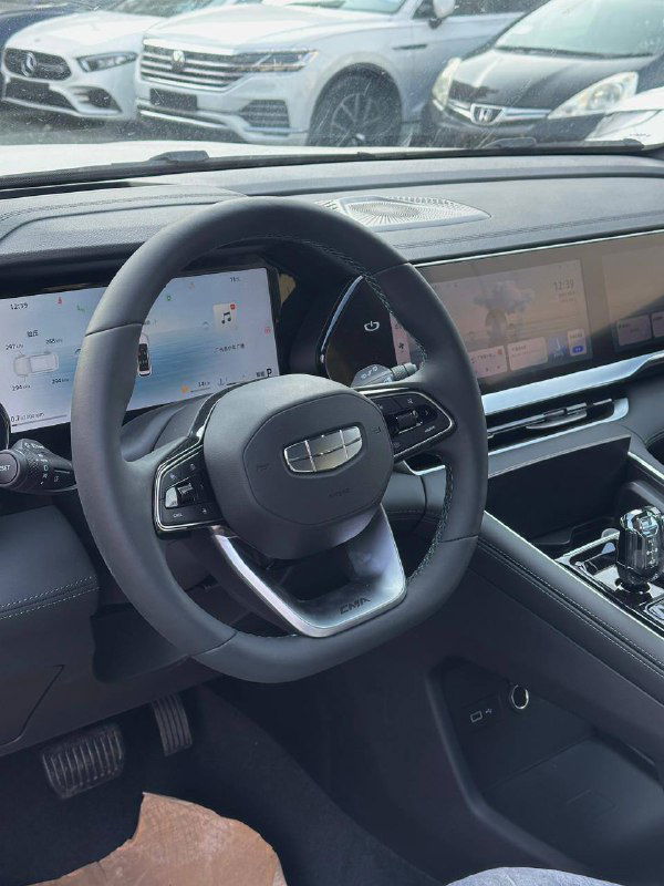 Вид с водительского места на рулевое колесо и часть передней панели Geely Monjaro 2025; видны кнопки на руле и экран мультимедиа.