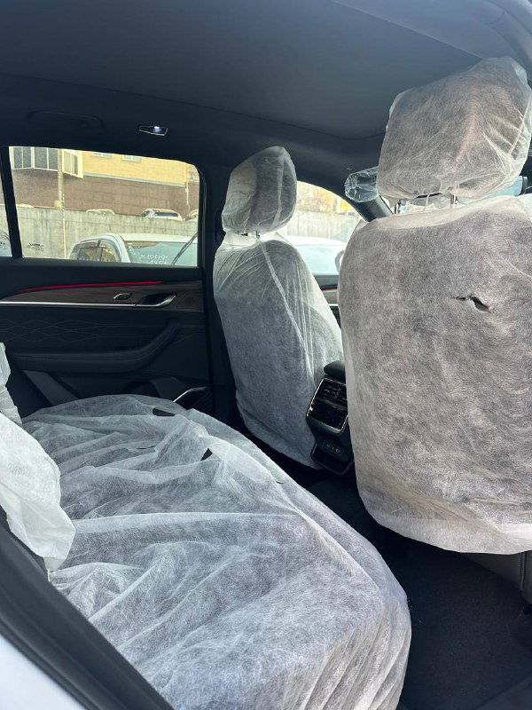 Задние сиденья Geely Monjaro 2025 в заводских защитных чехлах перед доставкой клиенту; видно пространство салона и подголовники.