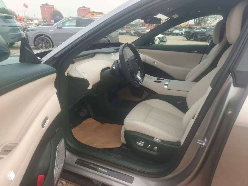 Открытая передняя дверь и вид на переднюю часть салона Xiaomi YU7 max: водительская зона, сиденье, часть дверной обивки и коврика.