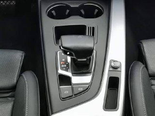 Центральная консоль Audi A4L с селектором коробки передач, подстаканниками и ручкой управления мультимедиа, вид крупным планом.