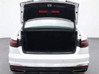 Открытый багажник белого Audi A4L 2022 года — вид сзади, пустое багажное отделение и элементы заднего бампера.