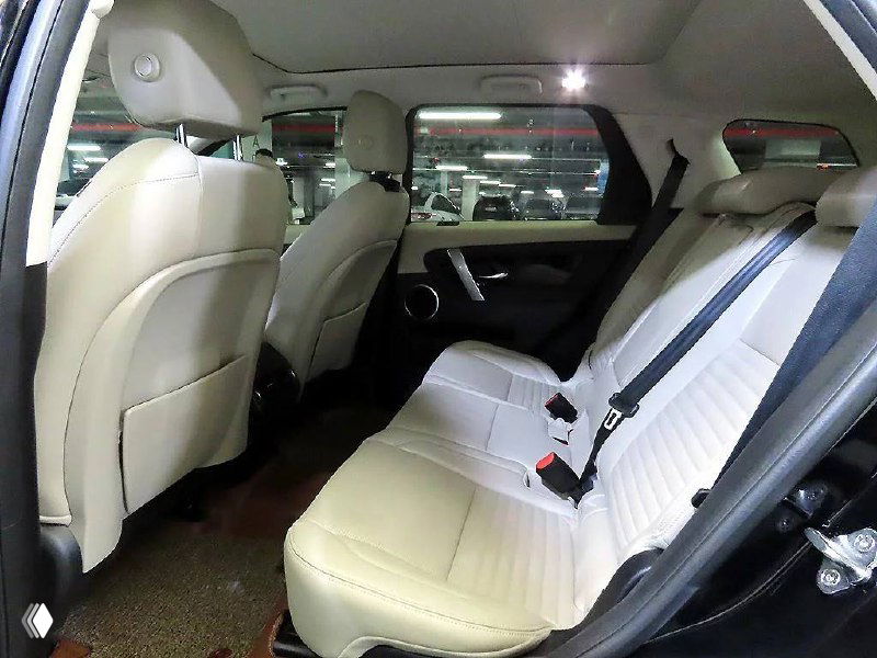 Задние сиденья Land Rover Discovery Sport 2020 года: бежевые кожаные кресла, ремни безопасности и пространство для пассажиров на заднем ряду.