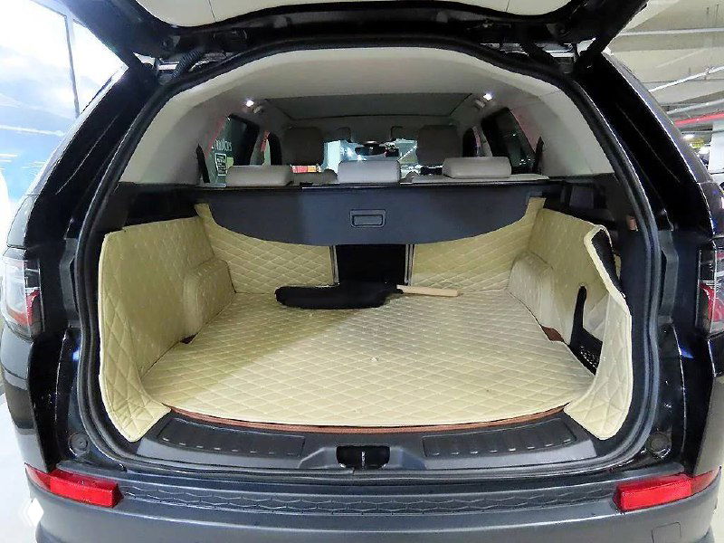 Багажник Land Rover Discovery Sport 2020 с поднятой крышкой, показано пространство багажника, ровный коврик и места для укладки груза.