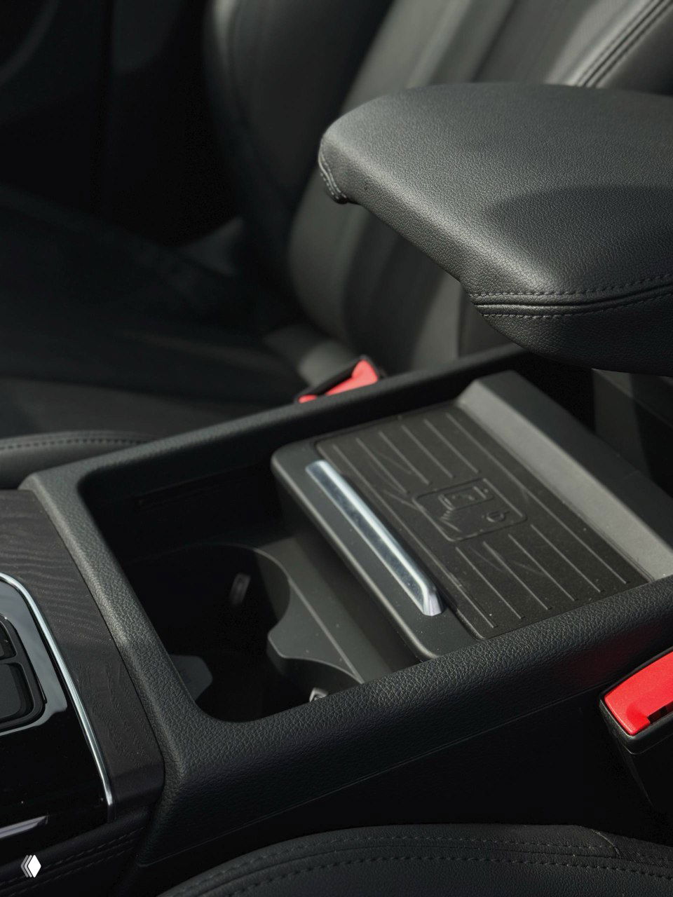 Передний подлокотник и ниша с подстаканниками в Audi Q5 — отделения для мелочей, глянцевая отделка и держатель телефона в центре.