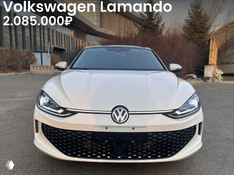 Фронтальный снимок Volkswagen Lamando 2022 года на открытой стоянке; белый кузов, видна решётка и фары, на фото указана цена 2.085.000₽, фон с деревьями.