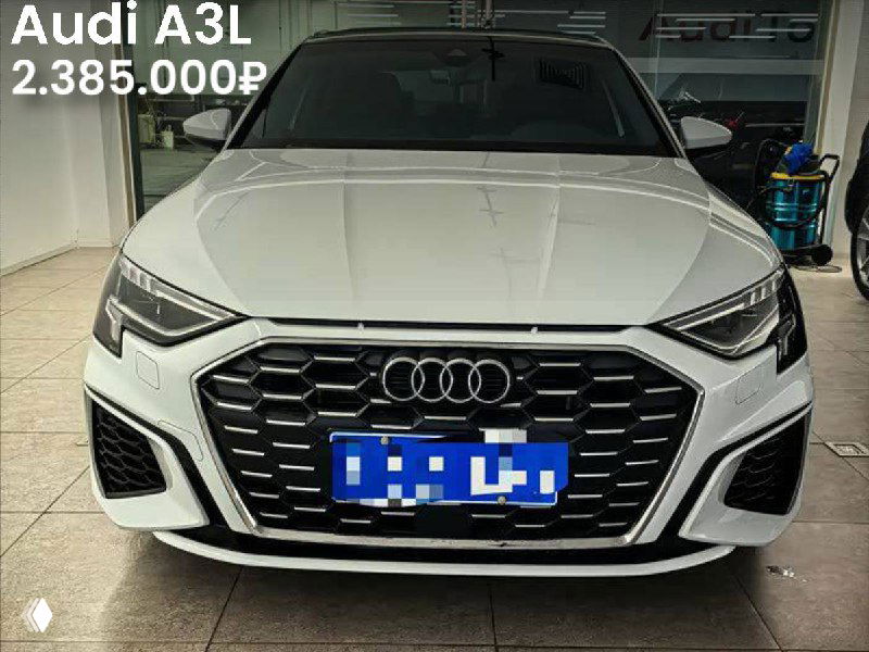 Фотография Audi A3L 2022 года спереди, белый кузов, выставлена на продажу в Китае; заметна решётка, табличка с ценой 2.385.000₽ и приглушённое освещение.