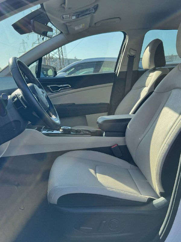 Передние сиденья KIA Sportage — бежевые кресла, подлокотник и обзор водительского места, салон в аккуратном состоянии.