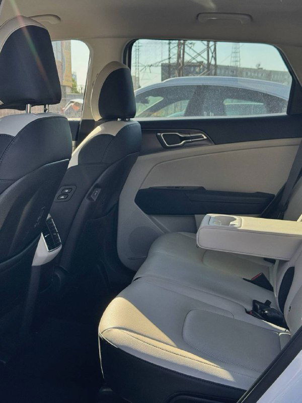 Задний ряд сидений KIA Sportage — простор для пассажиров, складной подлокотник и чистая обивка салона, вид со стороны двери.