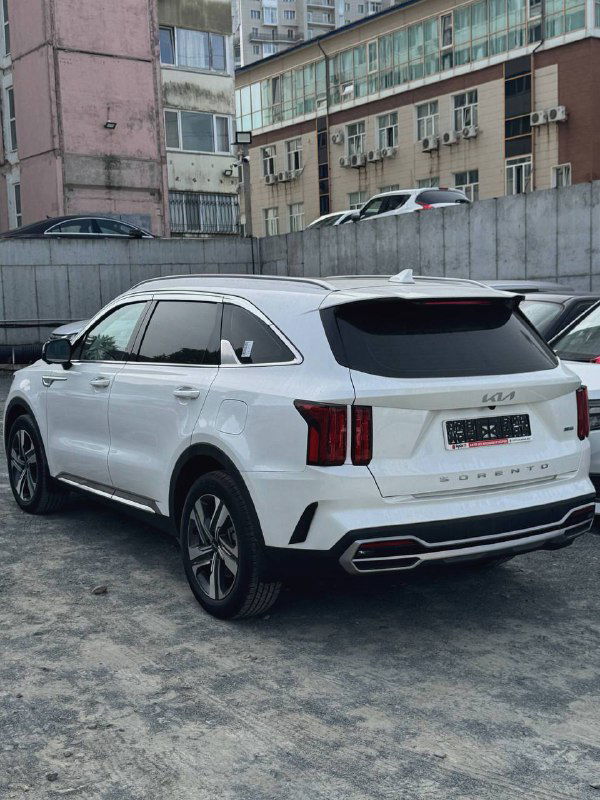 Вид сзади и боковой профиль белого KIA Sorento 2022 на парковке — видна форма багажника, задние фонари и общий профиль машины.