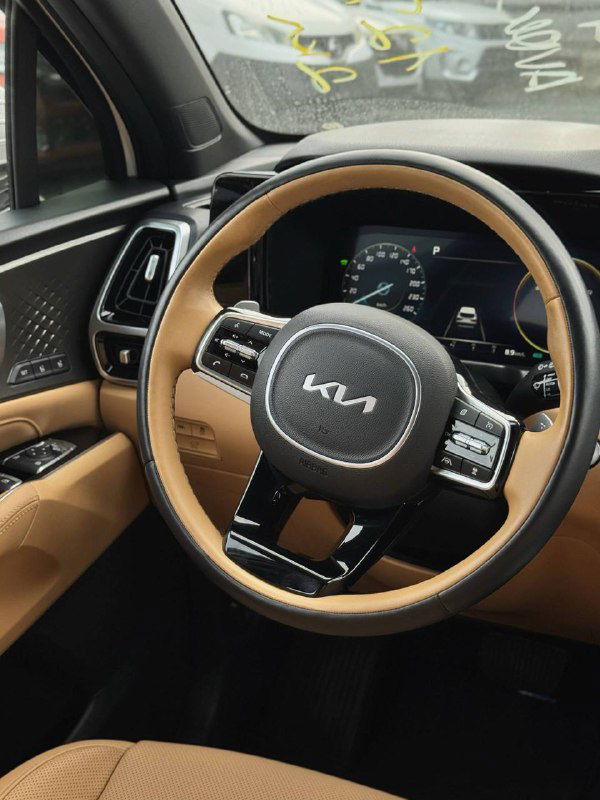 Крупный план руля KIA Sorento 2022 c фирменным логотипом KIA и элементами управления на руле, демонстрация качества отделки салона.