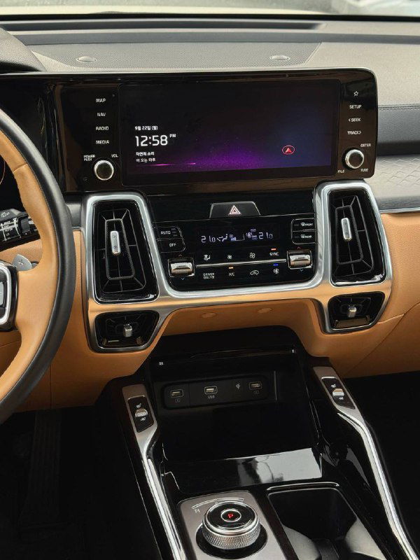 Центральная консоль и большой мультимедийный экран KIA Sorento 2022, показывает современный интерфейс и расположение кнопок управления климатом.