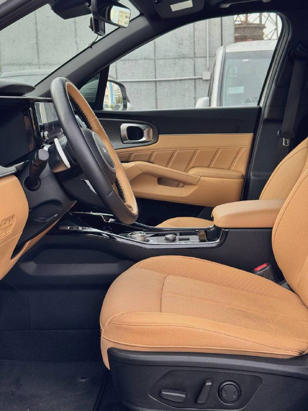 Передние сиденья и панорамный вид салона KIA Sorento 2022 с коричневой кожаной обивкой — демонстрация пространства и отделки салона.