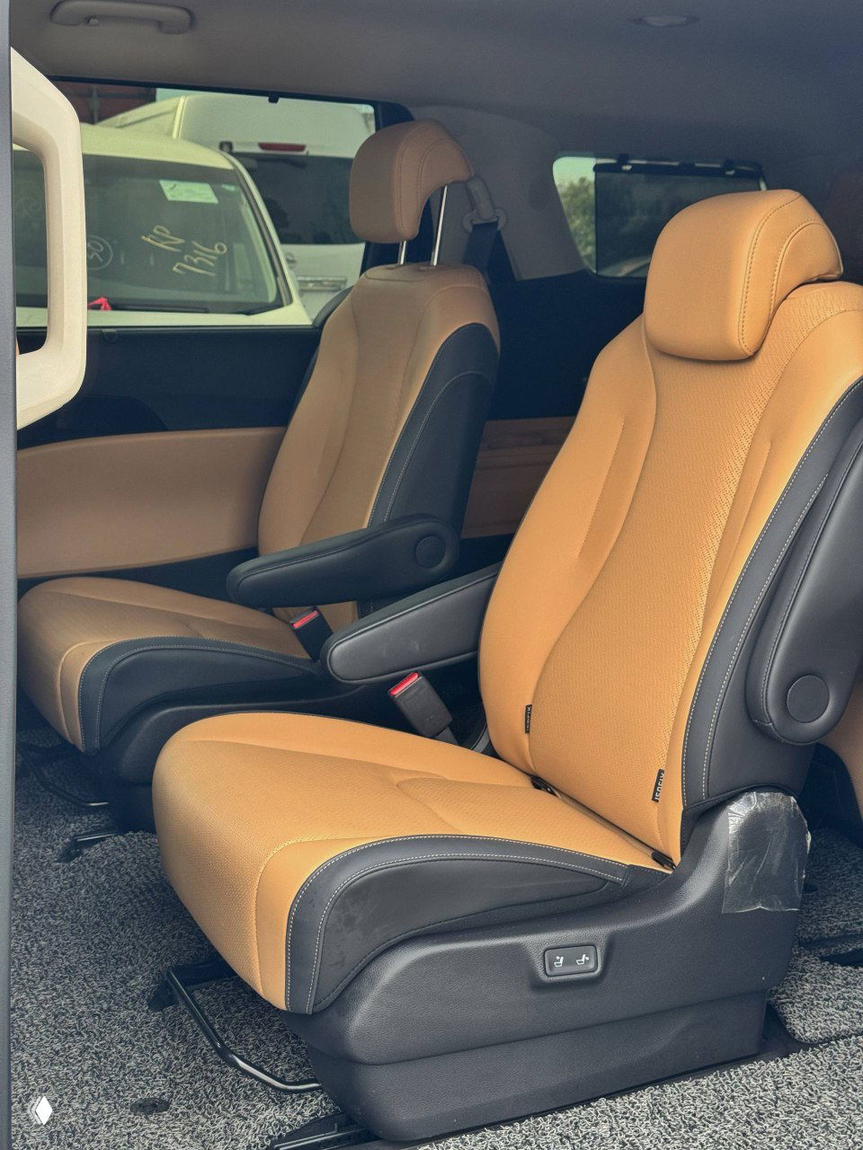 Рядные капитанские кресла второго ряда KIA Carnival в бежевой коже с подлокотниками, вид через сдвижную дверь.