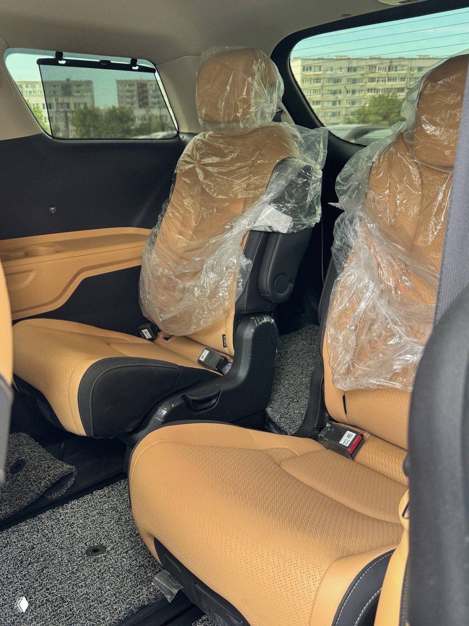 Третий ряд и упаковка защитной плёнки на головных подголовниках в салоне KIA Carnival, вид на внутреннее пространство и обшивку.