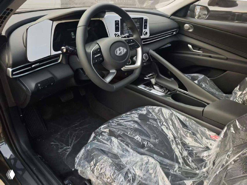 Интерьер новой Hyundai Elantra: передняя часть салона, руль, панель приборов и центральная консоль, сиденья в защитной плёнке.