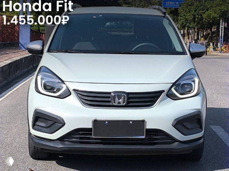 Фронтальный вид серебристого Honda Fit на парковке с видимым номером; на фото указана цена 1.455.000₽, дневное освещение.