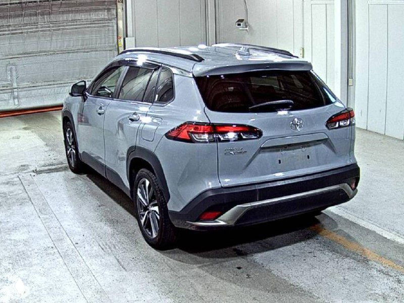 Toyota Corolla Cross 2022 вид сзади в ангаре аукционного склада; серый кроссовер без номерных знаков, готов к экспорту и погрузке.