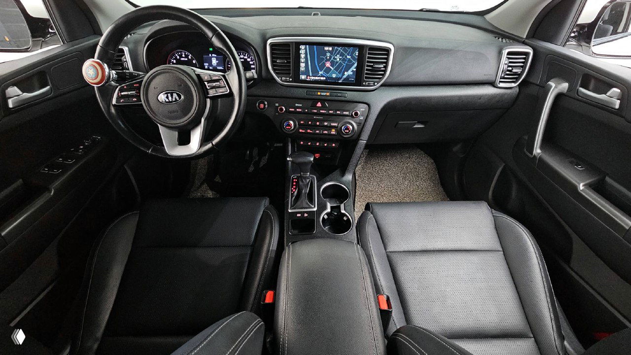 Интерьер KIA Sportage: передняя панель, мультимедиа с картой, рулевое колесо и передние сиденья в чёрной обивке — фото для оценки салона.