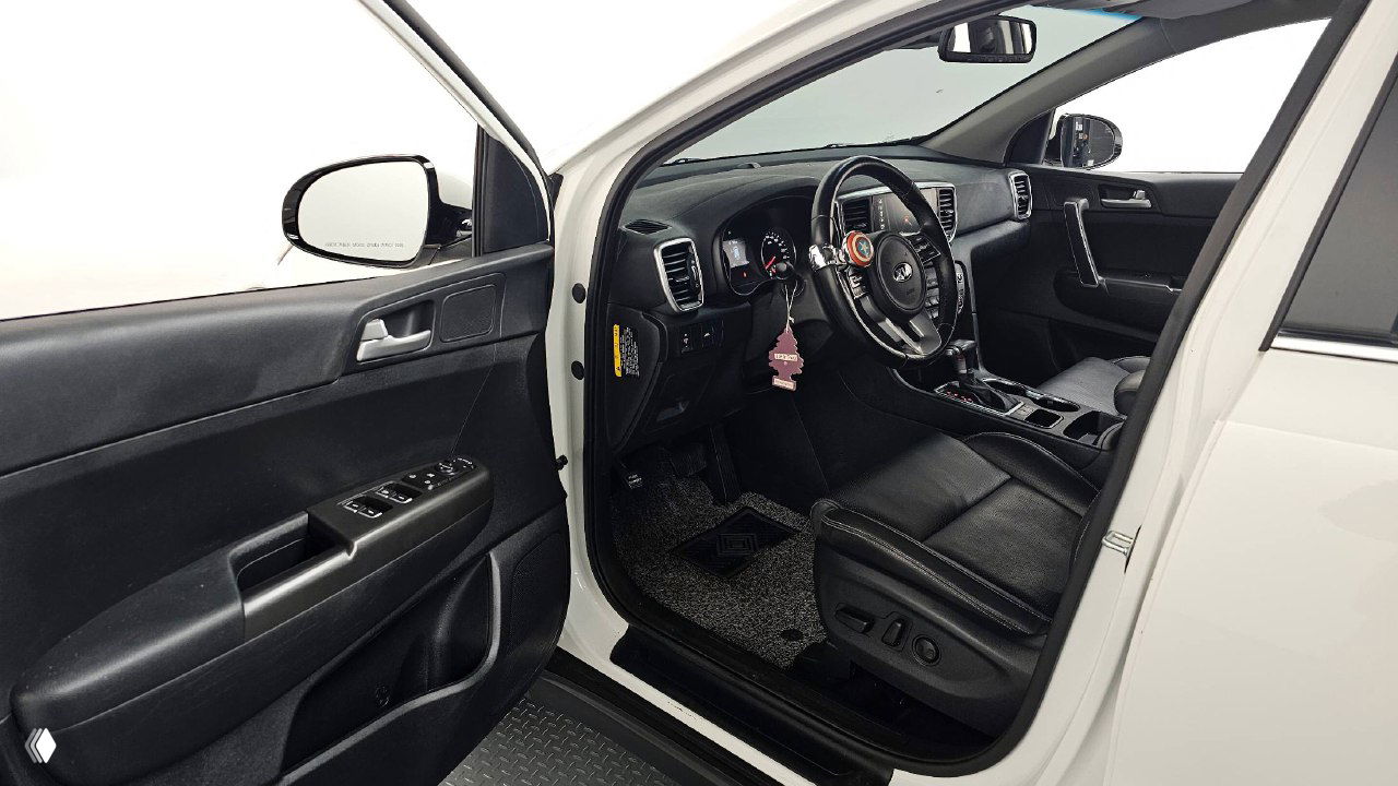 Открытая водительская дверь KIA Sportage, вид на переднее сиденье, управление стеклоподъёмниками и обивка дверей — обзор посадочного места.