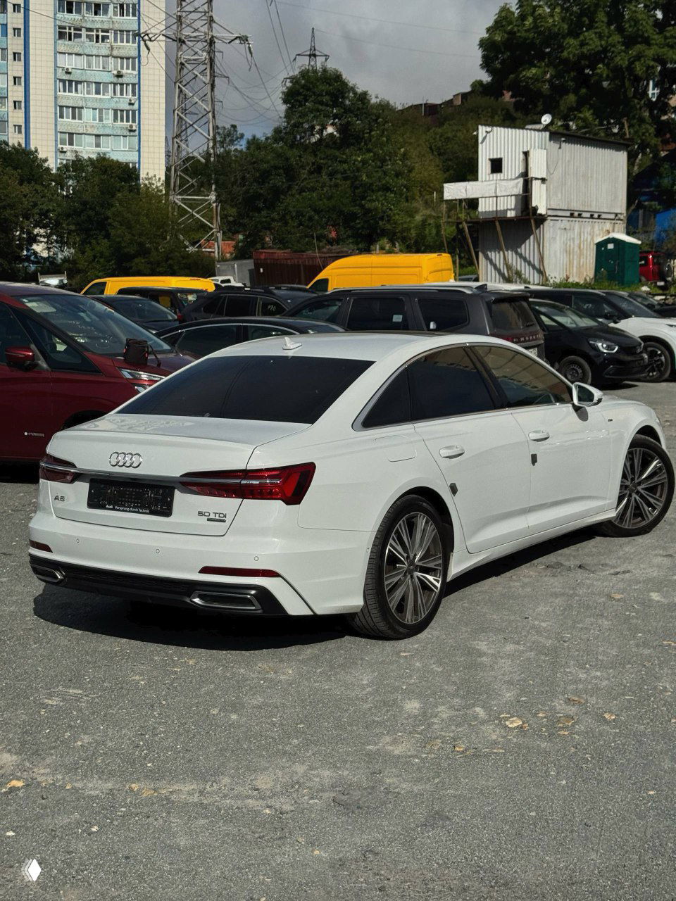 Белый Audi A6 50 TDI Quattro 2021 года вид сзади и в профиль, на задней двери эмблема A6 и отметка 50 TDI.