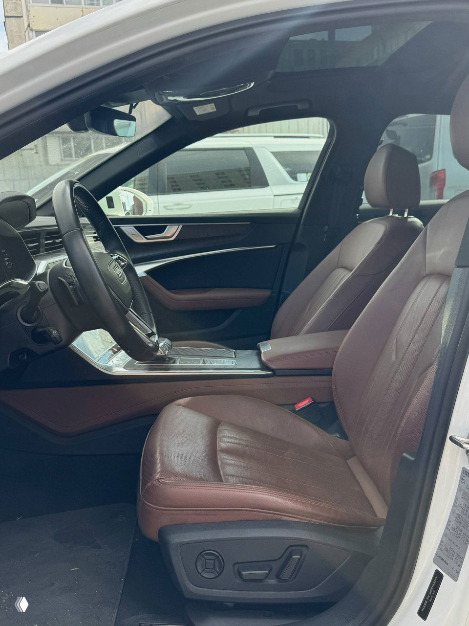 Водительское сиденье и передняя консоль Audi A6, коричневая кожаная отделка сидений и дверные вставки, общий интерьер.