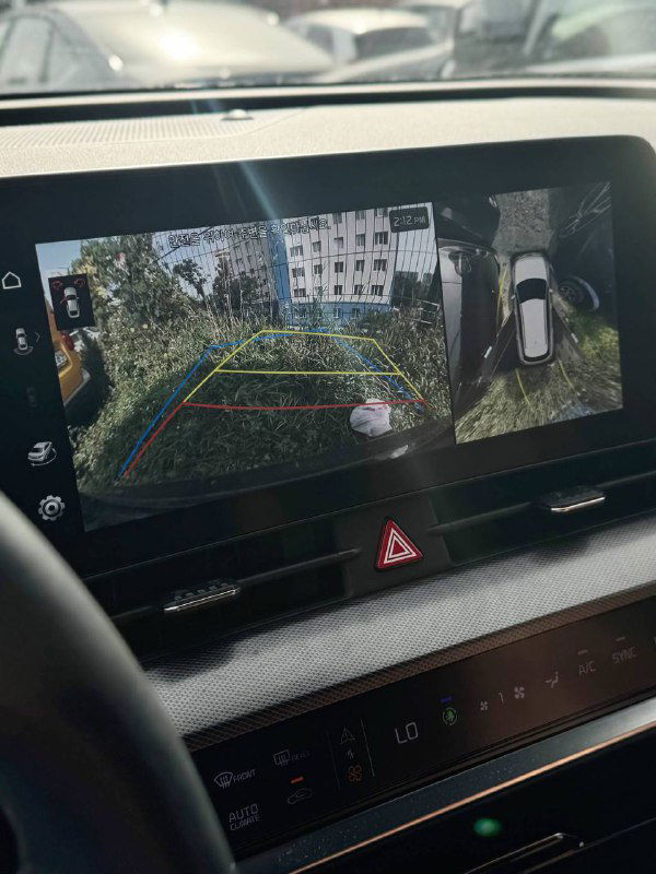 Экран мультимедиа и камера заднего вида KIA Sportage: отображение обстановки позади автомобиля с разметкой парковки на экране панели приборов.