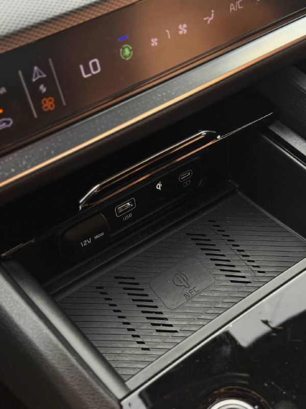 Отсек для беспроводной зарядки и порты USB в KIA Sportage, вид вблизи: текстурированная поверхность и удобное расположение разъёмов для гаджетов.