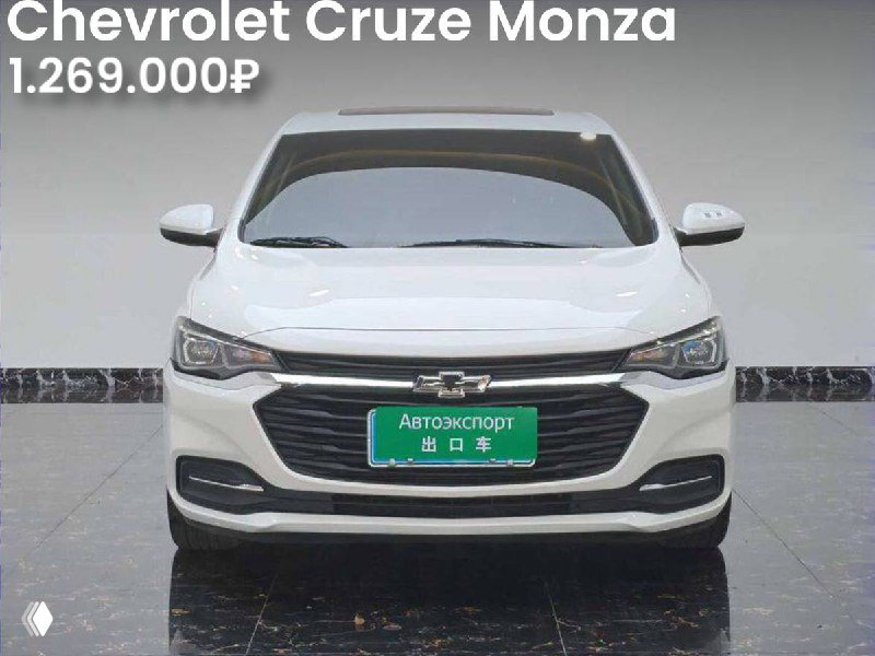 Фронтальный ракурс белого Chevrolet Cruze Monza в торговом пространстве; видна цена 1.269.000₽ и отметка «без окрасов».