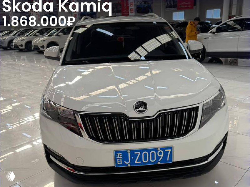 Фронтальный вид белой Skoda Kamiq в шоуруме с ценой 1.868.000₽; на снимке видно отсутствие окрасов и номерную табличку.