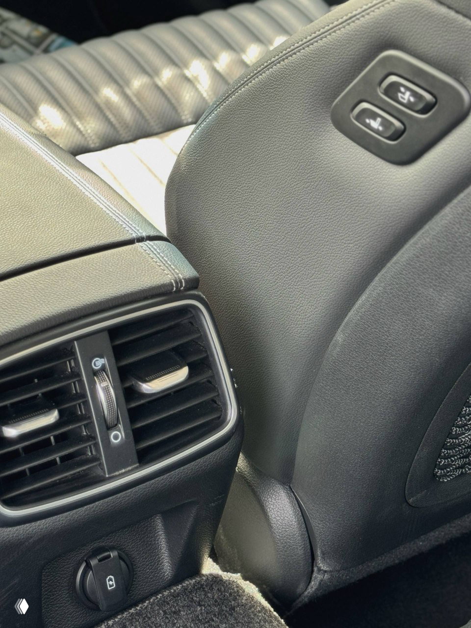 Крупный план заднего воздуховода и порта питания в салоне Genesis G70, детали отделки и состояния материалов для отчётности по импорту автомобиля.