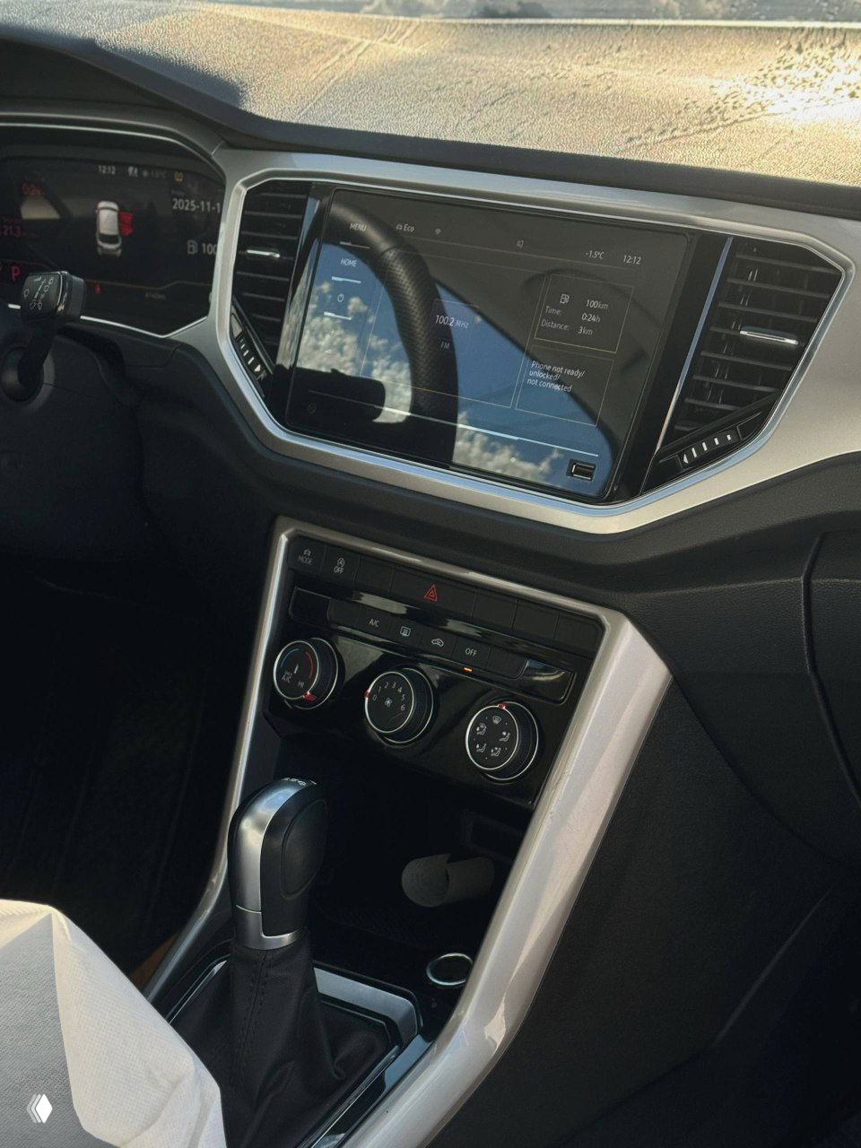 Мультимедийный экран и элементы управления климатом в центральной консоли Volkswagen T‑ROC — крупный план панели и рычага переключения передач.