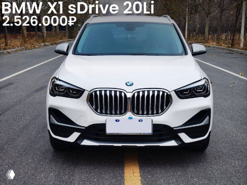 Фронтальный снимок белого BMW X1 sDrive 20Li 2022 года на дороге/площадке; видна решётка радиатора, фары, номерная панель и отметка цены и пробега.
