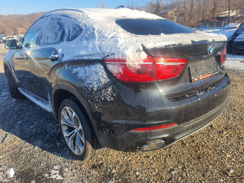 Вид сзади BMW X6 xDrive30d 2018 на стоянке, кузов частично покрыт снегом; видна задняя оптика, крышка багажника и задняя часть бампера.
