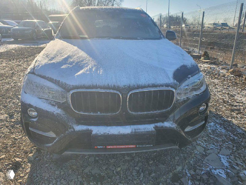 Фронтальный крупный план передней части BMW X6 xDrive30d 2018 с заснеенной капотом и характерной двойной решеткой радиатора.