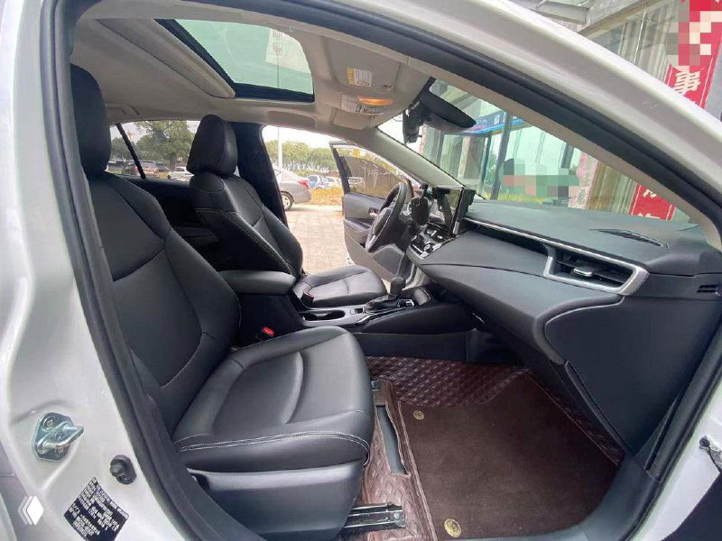 Передние сиденья и центральная консоль Toyota Corolla 2023, вид со стороны пассажирской двери; видно центральный тоннель и отделку салона.