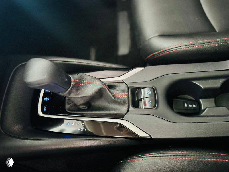 Фотография селектора переключения передач и центральной консоли Toyota Corolla 2022 — вид на рукоятку АКП, подстаканники и элементы отделки интерьера.