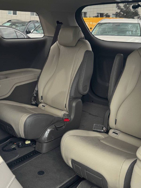 Отдельное пассажирское сиденье в заднем ряду KIA Carnival с широким подголовником и контрастной отделкой, вид на интерьер и пол багажного отделения.